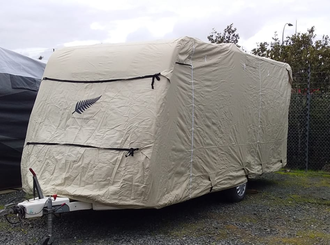 Image of caravan with a beige cover on and a silver fern